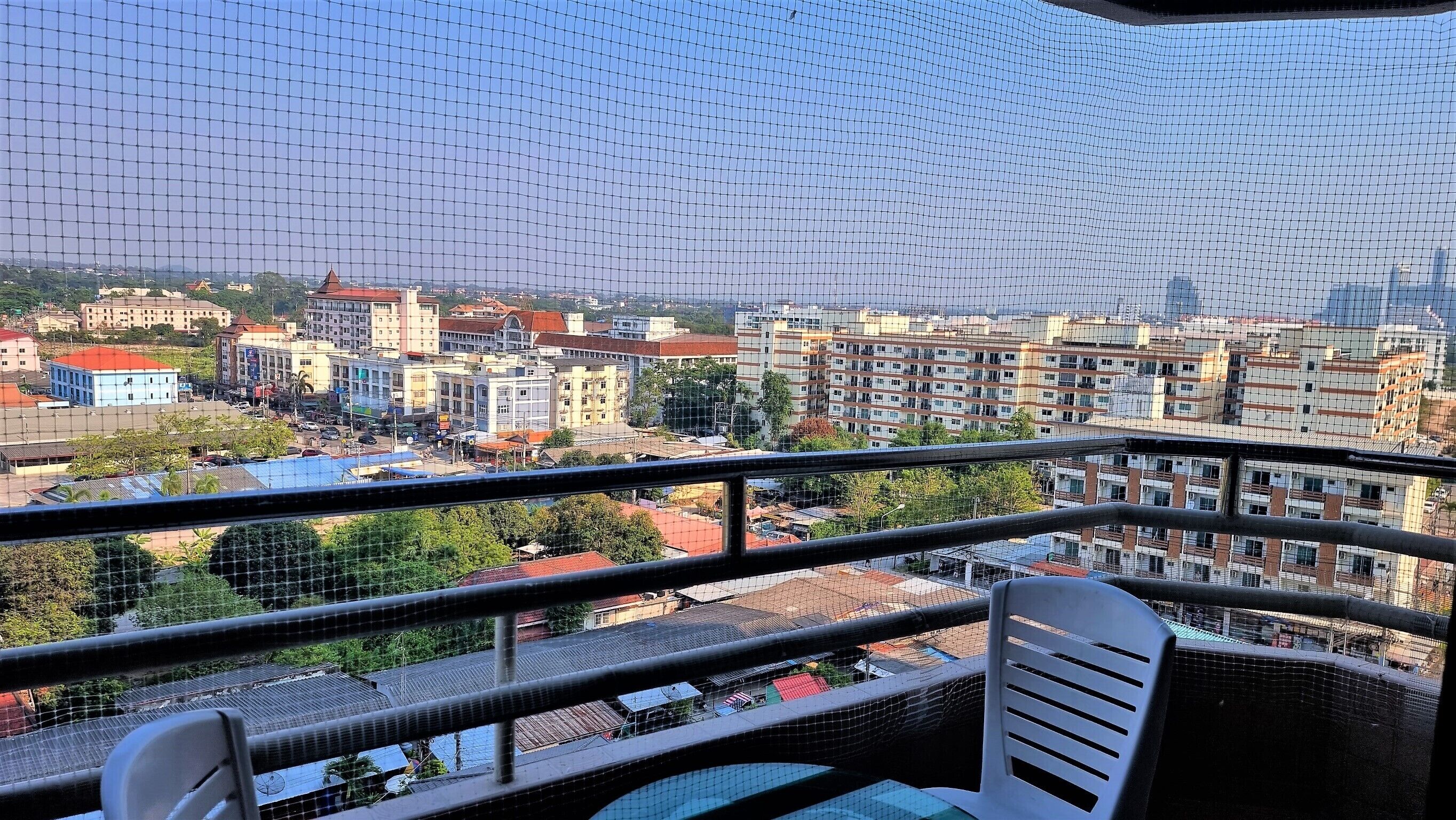Un balcon offrant une vue sur le paysage urbain, avec ses bâtiments et sa végétation.