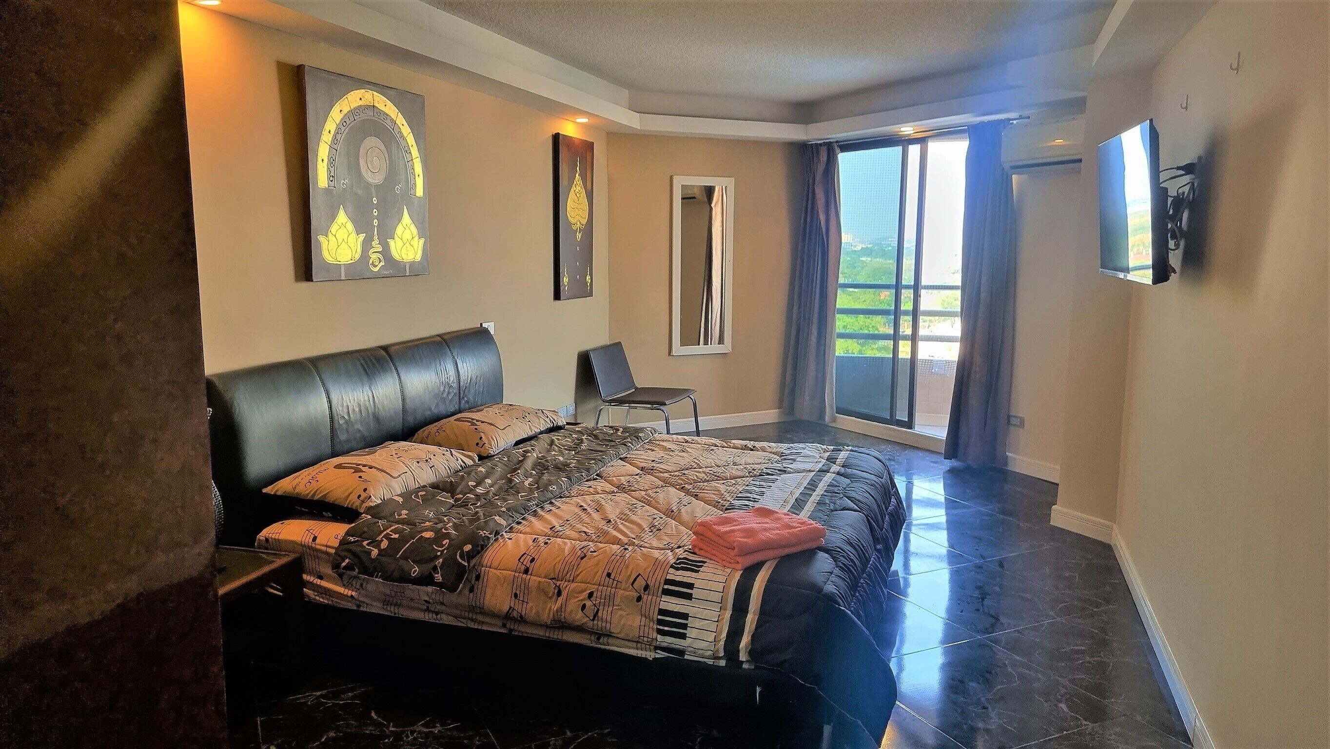 Una camera da letto con un letto, una sedia, un'ampia finestra e opere d'arte alle pareti.