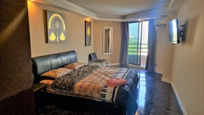 Ein Schlafzimmer mit einem Bett, einem Sessel, einem großen Fenster und Bildern an den Wänden.