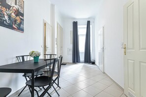 A dining area with a table and chairs, a potted plant, and a painting on the wall. - Affordable 2BR Apartment Near Belvedere (Vienna)