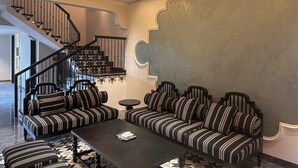 Un soggiorno con un divano a righe, un tavolino da caffè e una scala con corrimano.