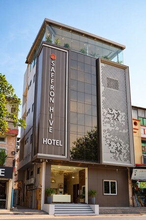 A modern hotel with a prominent sign, large windows, and a unique facade design. - Hotel Saffron Hive (Jodhpur)