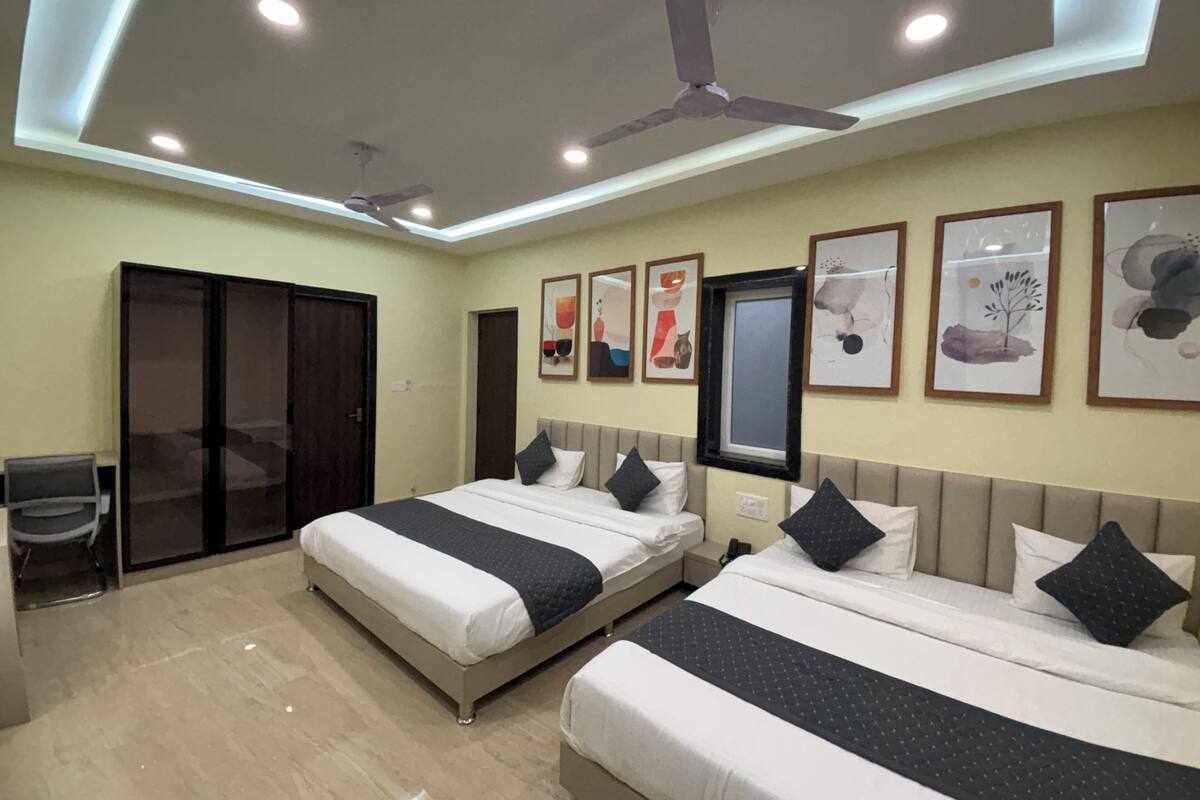 A hotel room with two beds, ceiling fans, recessed lighting, artwork on the walls, and a sliding door closet.