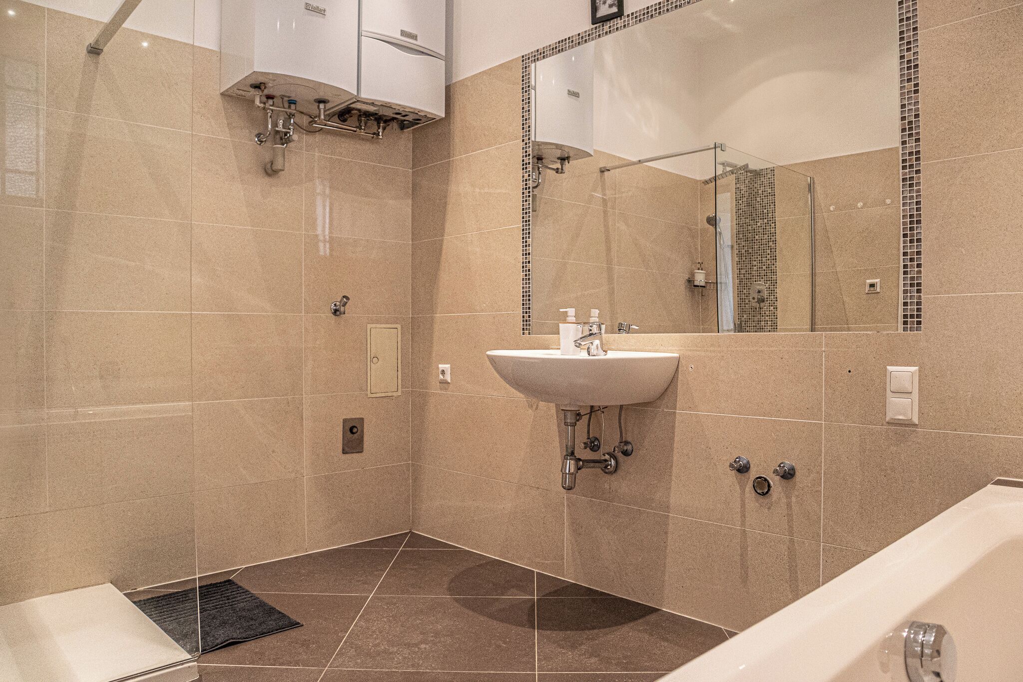 A modern bathroom with a sink, mirror, and shower.