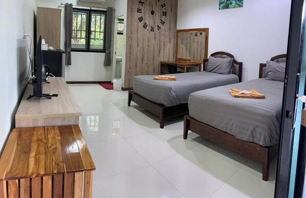 A hotel room with two beds, a wooden desk, a television, and a clock on the wall. - Plern Ping Cafe & Hotel (Bangkok)