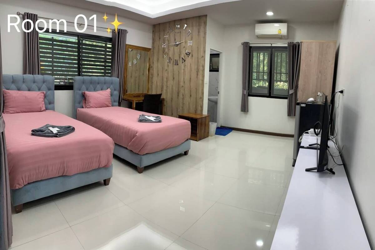 Una camera da letto moderna con due letti, una sveglia a muro in legno e una scrivania con un computer.
