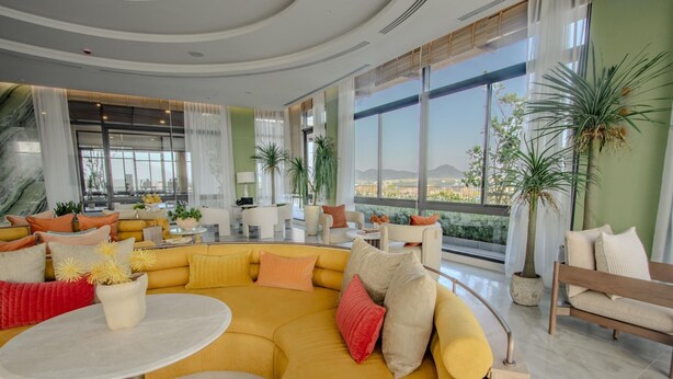 A spacious living area with a yellow sectional sofa, a round coffee table, and multiple seating options. - Canvas 111/2 2-bedroom Residence (Choeng Thale)