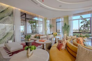 Un moderno vestíbulo de hotel con pared de mármol, ventanas amplias y plantas de interior.