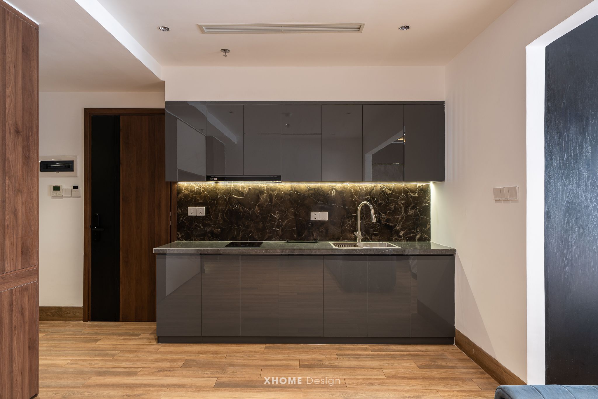 A modern kitchen with a marble backsplash, dark cabinetry, and a built-in sink.