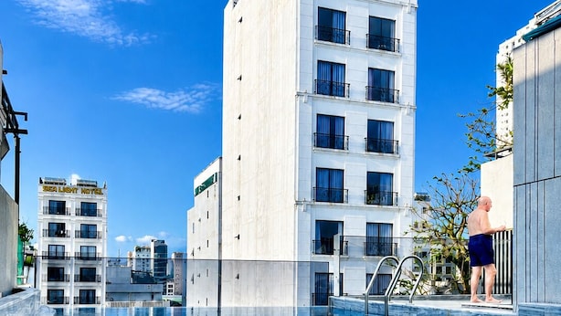 A swimming pool with clear blue water, surrounded by modern buildings and a clear sky. - La Anima Hotel & Apartment (Da Nang)