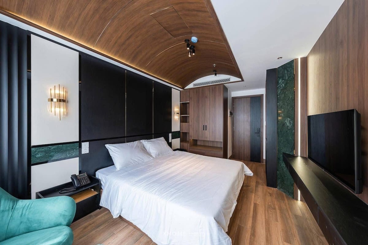 Una habitación de hotel moderna con una cama grande, televisión, escritorio y zona de estar.