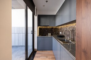 Una cocina moderna con un diseño elegante, que presenta una encimera oscura, un horno empotrado y un lavamanos de acero inoxidable.