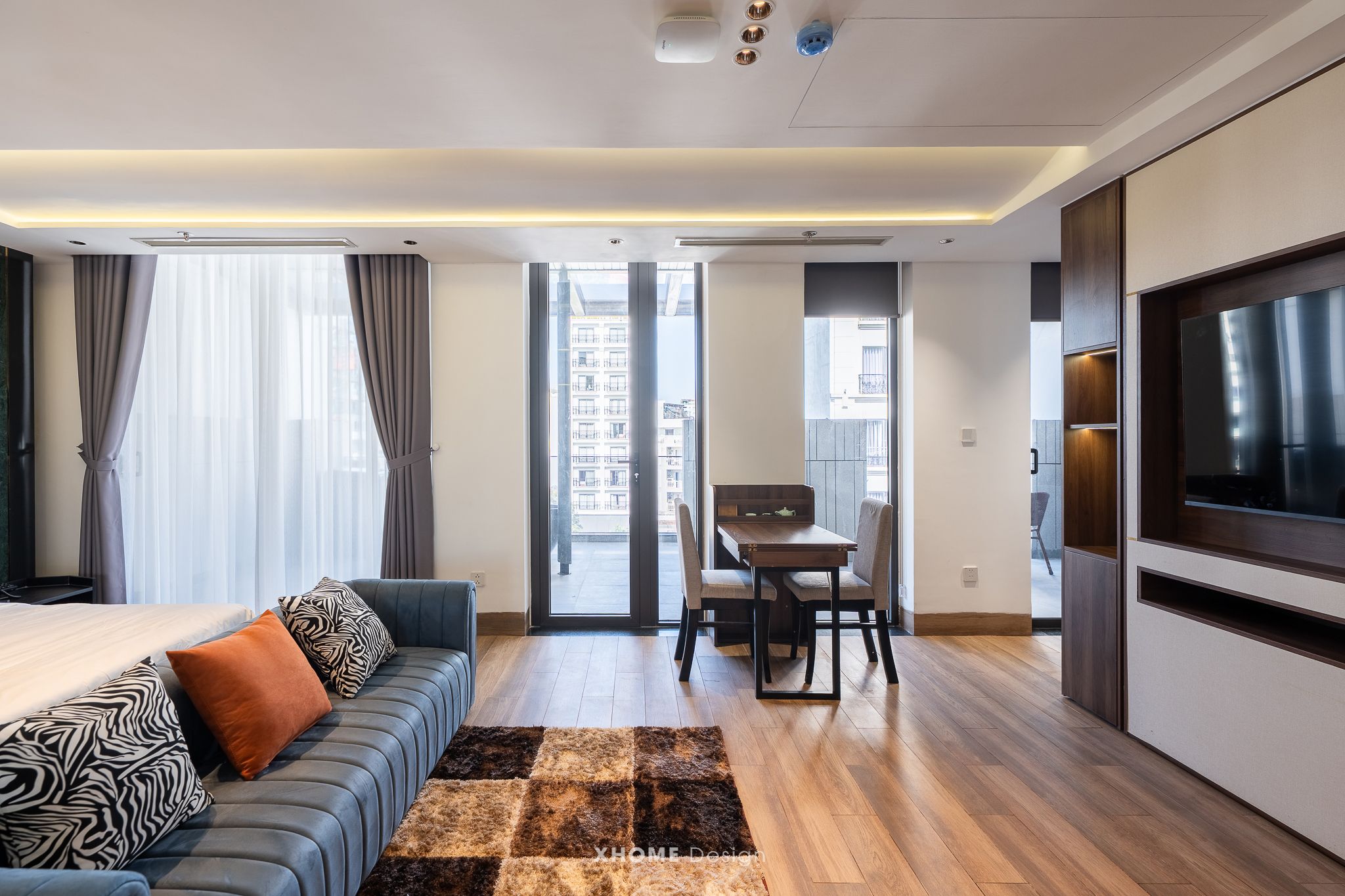 A modern hotel room with a sofa, a dining table, and a TV.
