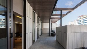 A corridor with glass doors leading to a room, a trash bin, and a view of buildings. - La Anima Hotel & Apartment (Da Nang)