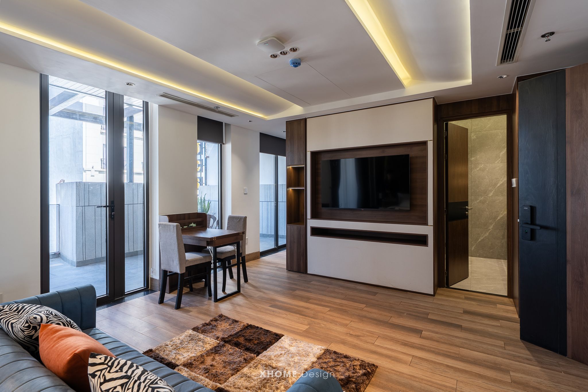Ein modernes Wohnzimmer mit einer Couch, einem Fernseher und einem Essbereich mit Tisch und Stühlen.