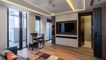 Ein modernes Wohnzimmer mit einer Couch, einem Fernseher und einem Essbereich mit Tisch und Stühlen.