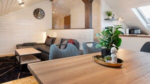 A modern interior with a wooden dining table, a sofa, and a kitchen area with a skylight. - Apartment 'Witt' with Whirlpool, Palm Garden, and Terrace (Salem)