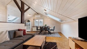 A loft-style room with a sloped ceiling, a dining area with a table and chairs, a sofa, and a TV. - Apartment 'Witt' with Whirlpool, Palm Garden, and Terrace (Salem)