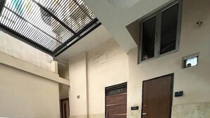 A spacious indoor area with a tiled floor, potted plants, and a large wooden door. - Hotel Kelson DX-Near Ramakrishna Metro (New Delhi)
