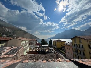 A residential area with terracotta-tiled roofs, a view of the lake, and mountains in the background. - Studio 7 (Nago-Torbole)