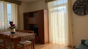Un comedor con una mesa y sillas de madera, una estantería y un reloj de pared grande.
