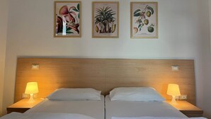 A hotel room with two beds, a wooden headboard, and three framed botanical illustrations on the wall. - Family Baia 6 (Nago-Torbole)