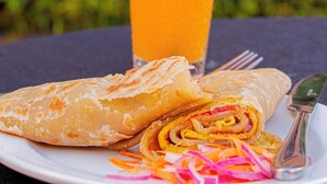 Un plato con un pastel enrollado y un vaso de jugo de naranja con pajita.