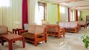 Habitación de hotel con sofás a rayas, una mesa de centro de madera y una televisión.