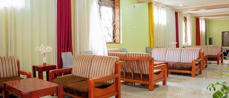 A hotel room with striped sofas, a wooden coffee table, and a television.