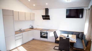A compact kitchen with a dining area, built-in appliances, and a flat-screen TV.