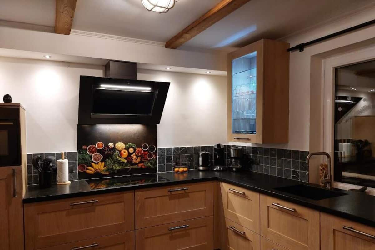 Eine moderne Küche mit Holzausstattung, schwarzen Arbeitsplatten und einem eingebauten Backofen.