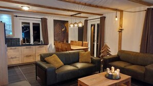 Un salon moderne avec un canapé, une table basse en bois et un coin repas comprenant une table et des chaises.