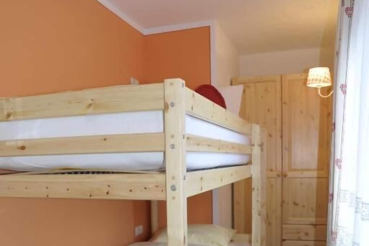 Ein Schlafraum mit Etagenbetten, Holzwänden und einem Kleiderschrank.