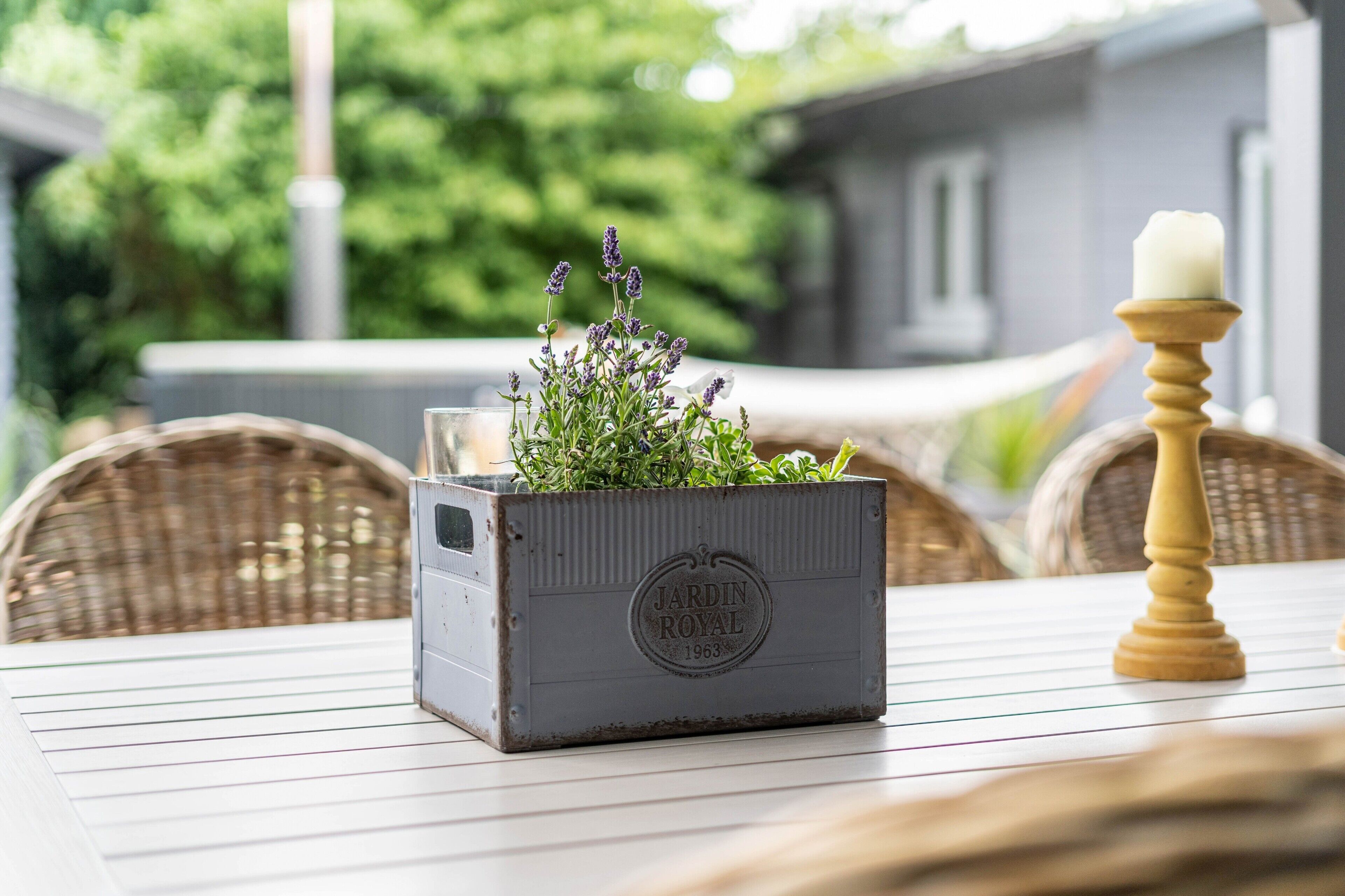 Un pot de fleurs en métal au style rustique, avec une plante et une bougie posés sur une table.