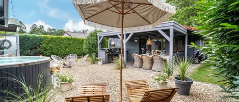 A covered outdoor seating area with a table and chairs, a hot tub, and a pergola with a hanging light.