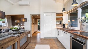 Une cuisine moderne avec des armoires blanches, un plan de travail en bois et un four encastré.