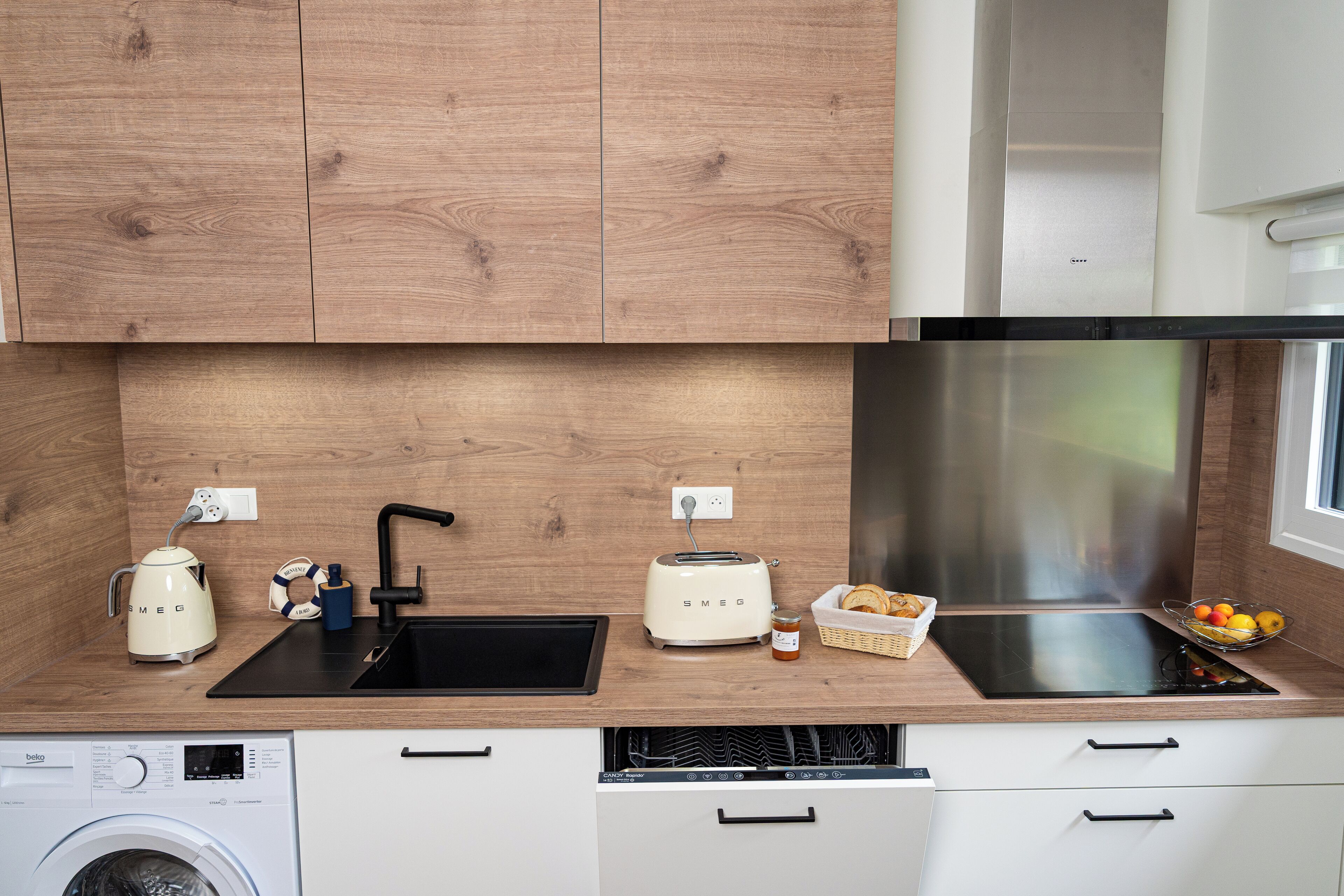 A modern kitchen with wooden cabinets, a black sink, a toaster, and a built-in oven.