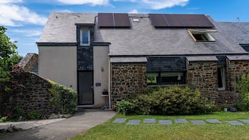 Un bâtiment en pierre avec un toit en pente, une petite fenêtre et une porte.