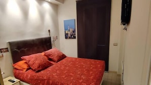 Een slaapkamer met een bed, nachtkastje en een schilderij aan de muur.