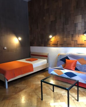 Una habitación con cama, sofá, mesa de centro de cristal y paneles de madera en las paredes.