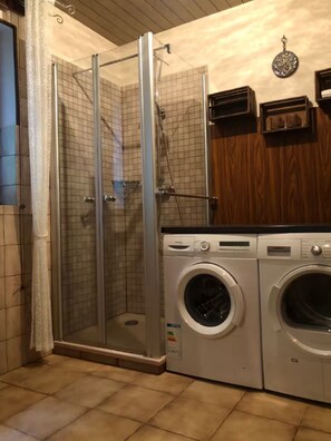 Un baño con ducha de vidrio, lavadora y secadora.