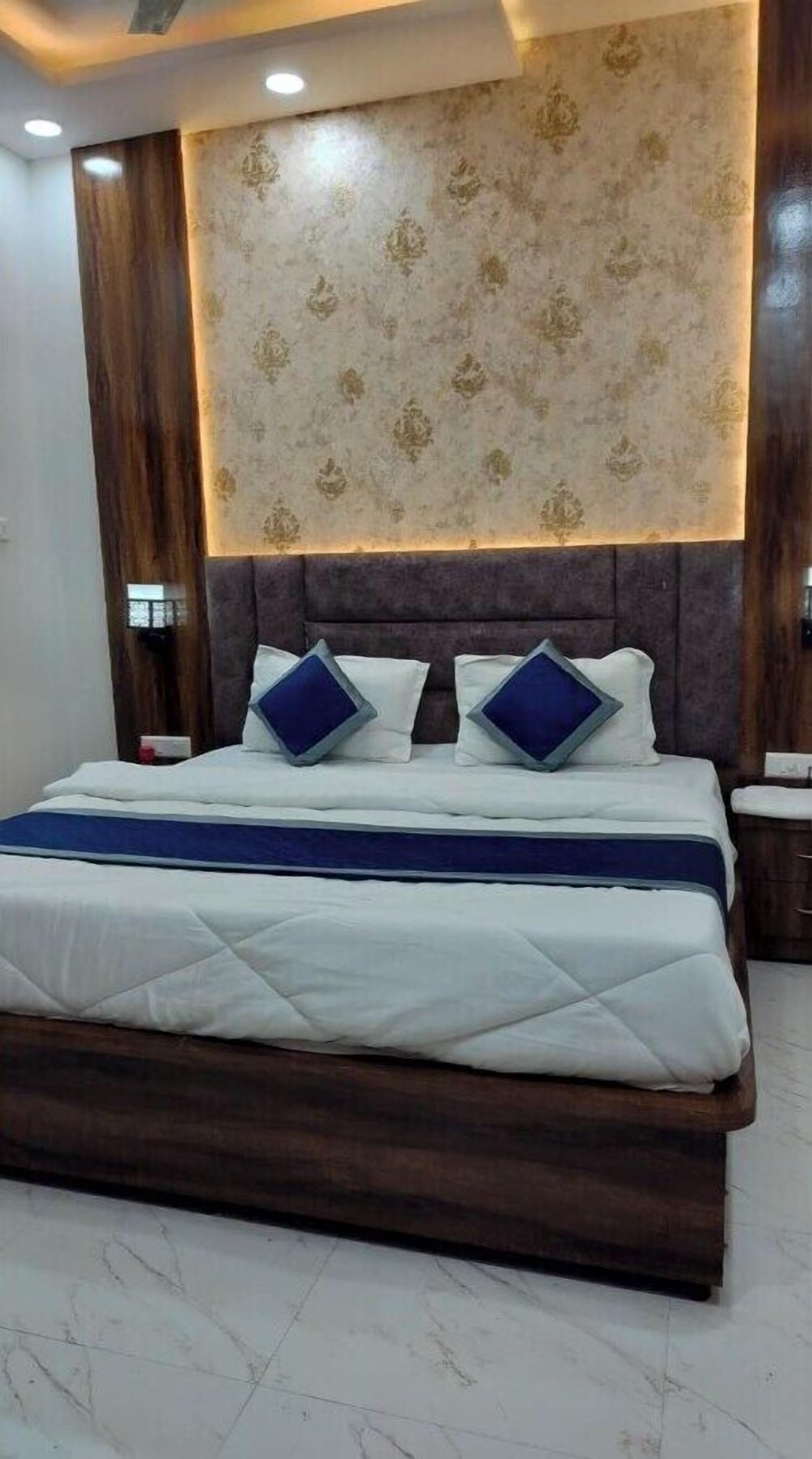 A bedroom with a large bed, dark wood headboard, and patterned wallpaper.