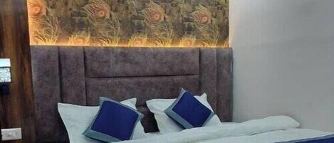 A bedroom with a bed, a headboard, a ceiling fan, and a wall with a decorative pattern.