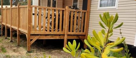 A mobile home with a wooden deck and a covered porch.