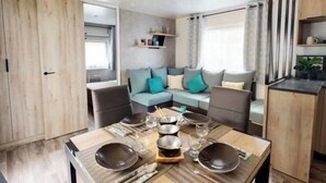 A modern, open-plan living space with a dining area, sofa, and kitchen. - Bungalow between nature and ocean at Le Ferret, a 4* resort with aquatic areas (Lège-Cap-Ferret)