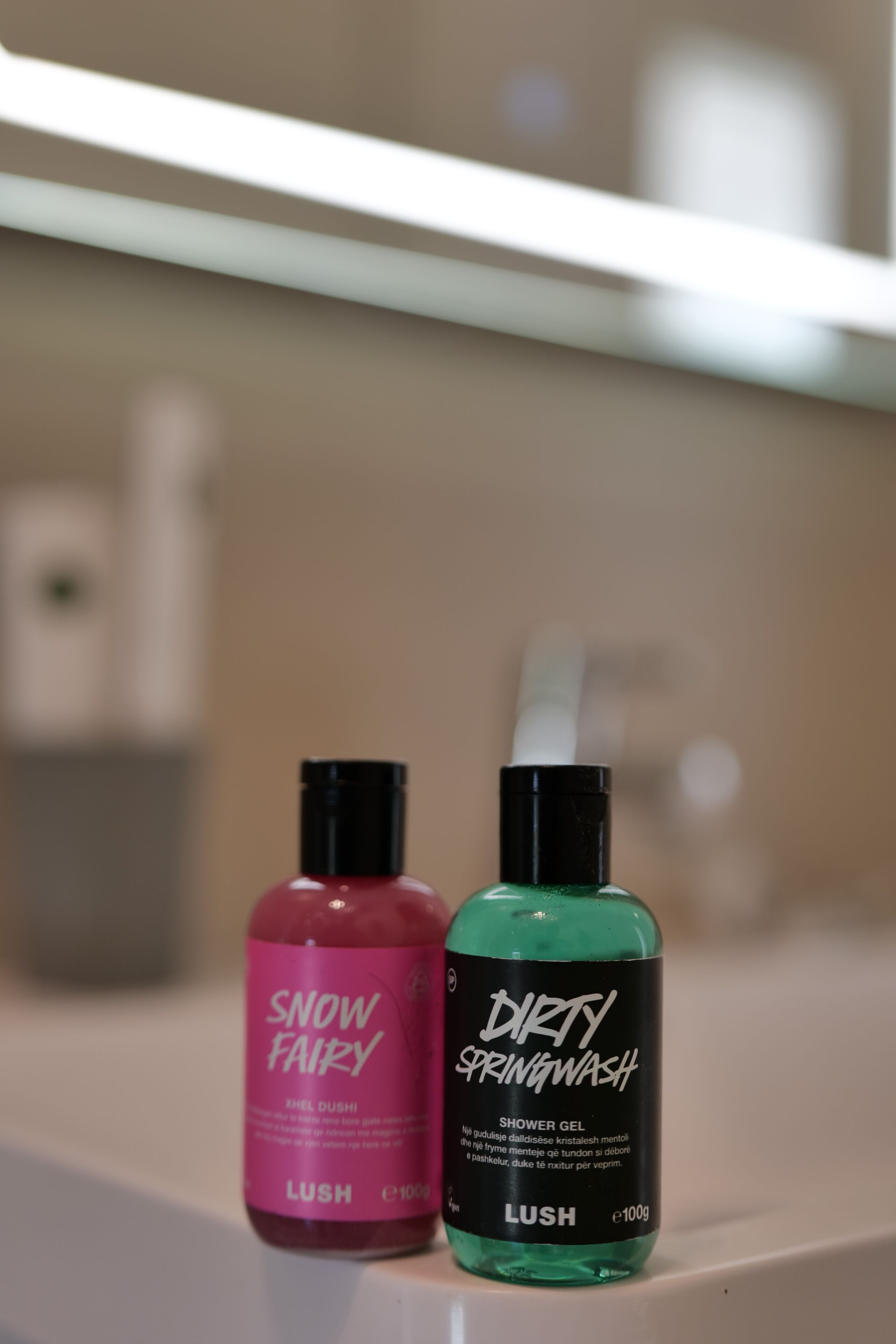 Two bottles of shower gel on a bathroom counter.