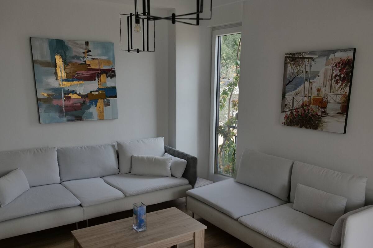 Un saló modern amb un sofà en forma de L, una taula de centre i dos quadres a les parets.