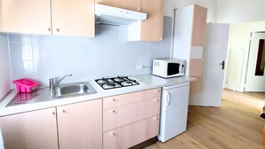 Een keuken met een gasfornuis, magnetron, spoelbak en kastjes.