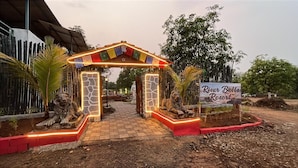 A gated entrance with a sign for River Bellas Resort, featuring a stone archway and illuminated lights. - Riverbell Selfie Point Cottage (Shahapur)