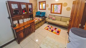 Una sala de estar con un sofá, una mesa de centro, un aparador de madera y un tapete estampado.